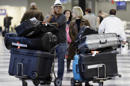 FILE - In this Dec. 1, 2013 file photo, travelers walk through terminal 3 baggage claim at O'Hare International airport in Chicago. The government reported Monday, May 5, 2014, that U.S. airlines raised $3.35 billion from bag fees in 2013, down 4 percent from 2012. That’s the biggest decline since fees to check a bag or two took off in 2008. (AP Photo/Nam Y. Huh, File)